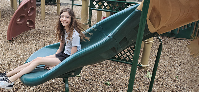 CHoR patient Astrid Luck smiling on a slide at the playground