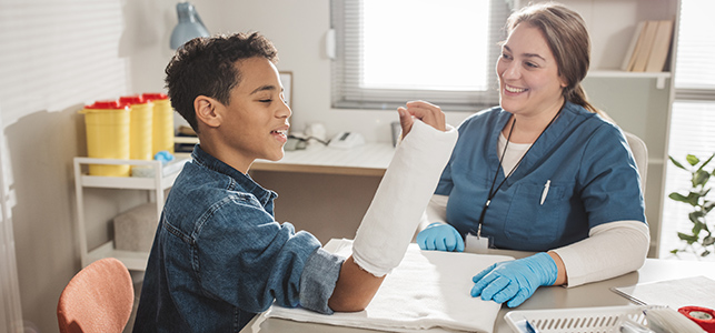 Smiling nurse putting cast on boy's arm