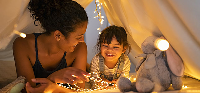 Mom and daughter with holiday lights and stuffed animal