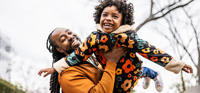 Father holding his daughter up in the air outside