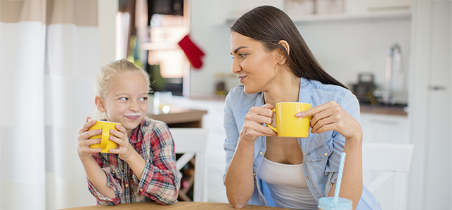 Mom and daughter drinking milk from yellow coffee mugs