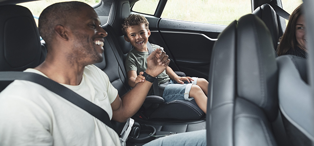 Dad wearing seat belt in back seat of car with his child
