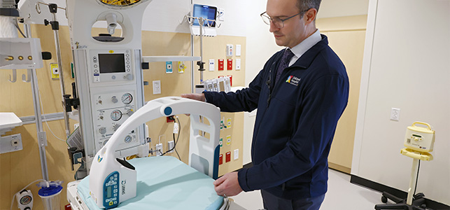 Dr. Samuel Casella shows the mini C-Arm on a NICU bed at CHoR