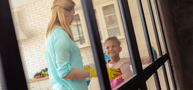 Mom and daughter wearing rubber gloves and cleaning windows