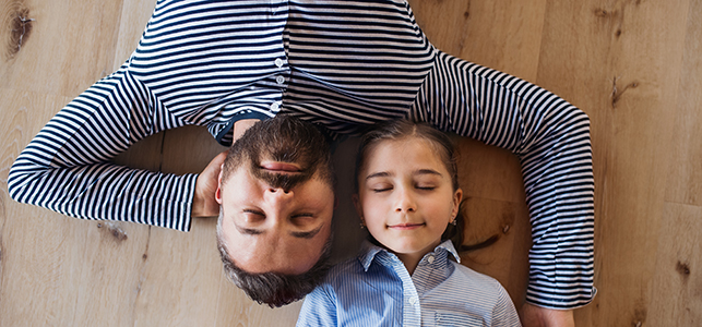 Dad and daughter lying on floor with eyes closed