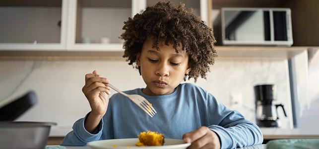 Child holding fork and looking at plate of food
