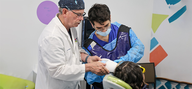 A VCU dental student receives guidance while providing free care at Give Kids a Smile