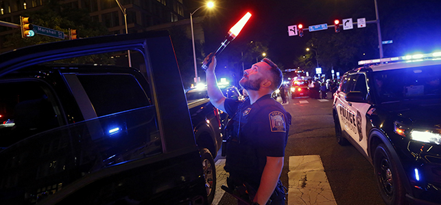Police officer standing on dark street waving lit wand and looking up