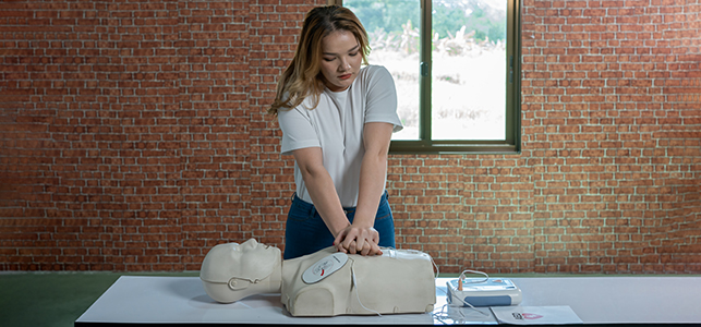 Woman practicing hands-only CPR on a mannequin
