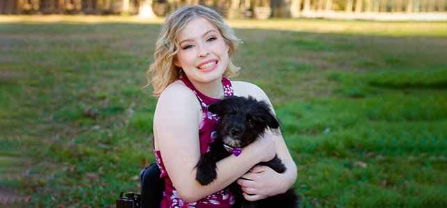 CHoR patient Hannah Smith smiling and holding her puppy outside