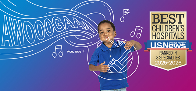 CHoR patient Ace playing a pretend tuba with the U.S. News Best Children's Hospitals seal next to him