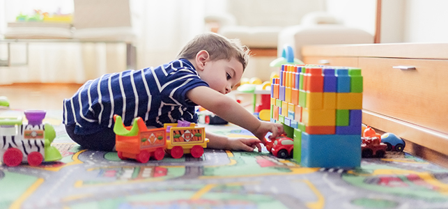 Child playing on the floor with blocks and toy cars
