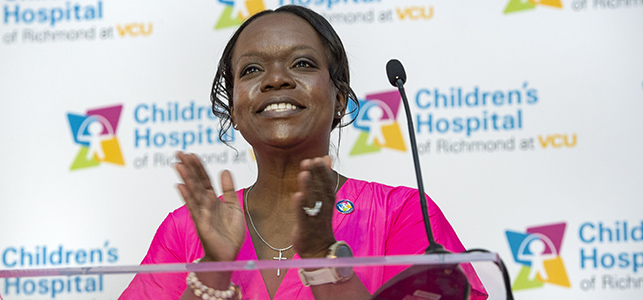 CHoR leader Jeniece Roane clapping at podium during Children's Tower ribbon cutting