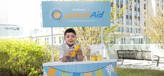 2026 Anthem LemonAid Ambassador John Modi standing in a lemonade stand