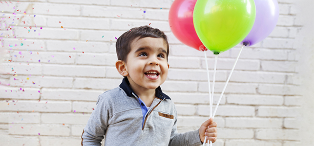 Young boy holding balloons and smiling