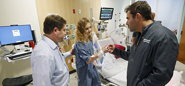 Cardiac surgeon Dr. Brian Kogon fist bumps a patient in a CHoR PICU room