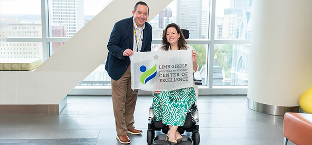 CHoR's Dr. Nicholas Johnson and Kathryn Bryant Knudson hold a Limb Girdle Muscular Dystrophy Center of Excellence flag