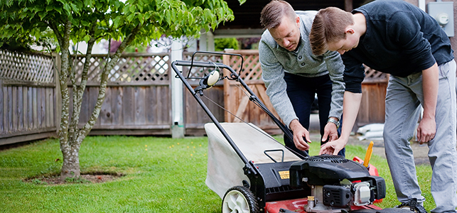 Dad inspecting the lawn mower with teen son