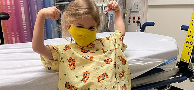 CHoR neurosurgery patient Madison smiling and flexing in her hospital gown
