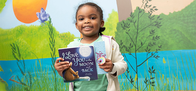 CHoR patient holding a book donated to the hospital by Markel