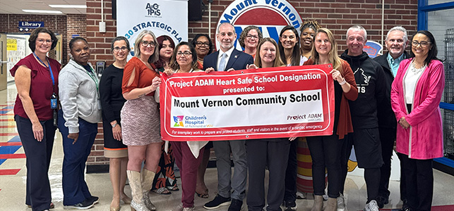 CHoR's Dr. John Phillips holding a heart safe school banner with team from Mt. Vernon Community School