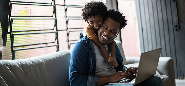 Dad and child looking at laptop at home