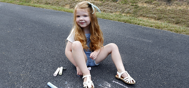 CHoR patient Olivia Rudesheim drawing with chalk on the driveway