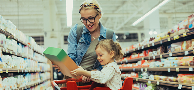 Mom and daughter look at cereal box at grocery store