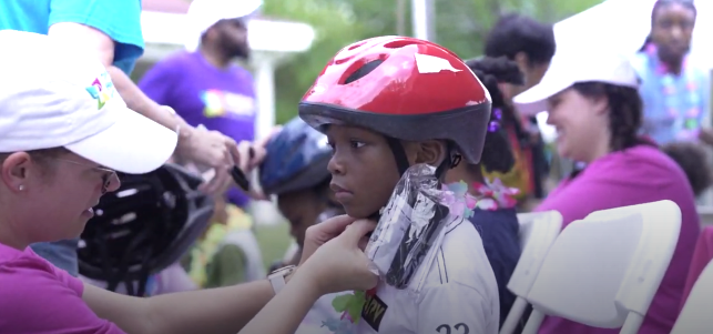 Volunteer fits free bicycle helmet at CHoR safety fair