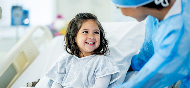 Girl in hospital bed smiling at surgeon