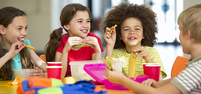 Four elementary school students eating lunch together