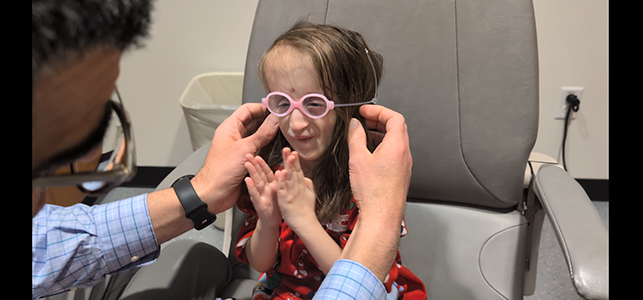 CHoR patient Selena smiling in her pink glasses and clapping