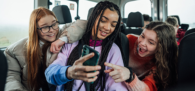 Three teen girls smiling and looking at phone