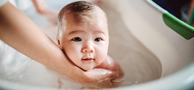 Baby getting hair washed as parent looks at soft spot