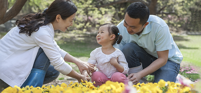 Parents and young daughter smiling in spring garden