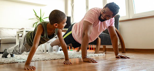 Dad and son doing pushups on living room floor