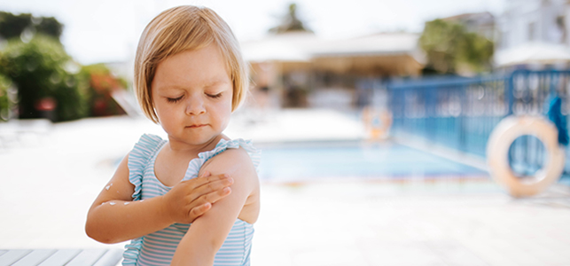 child applies sunscreen near pool