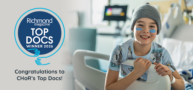 CHoR patient smiling in hospital bed with gray stocking cap and blue eye paint