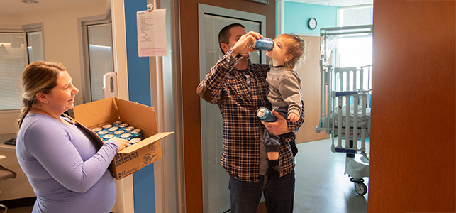 CHoR nurse gives canned water to a young patient and his dad