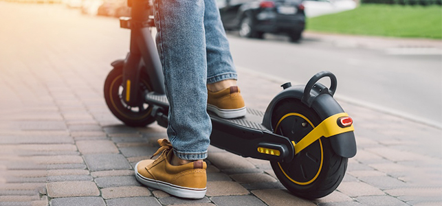 Older child's feet on a black and yellow electric scooter